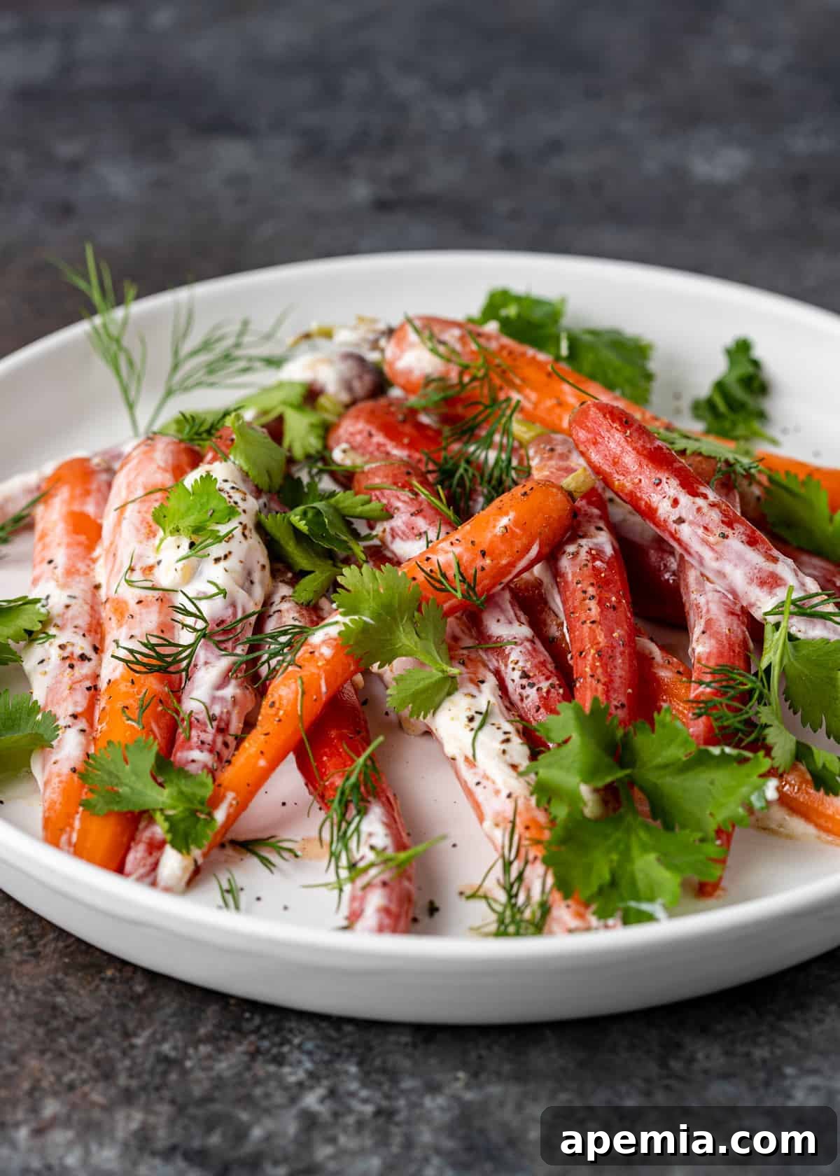 A vibrant baby carrot recipe featuring heirloom steamed carrots generously coated in a creamy yogurt sauce, garnished with fresh herbs, and ready to be served.