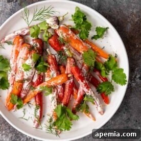 Overhead shot of a round white plate featuring Moroccan steamed carrots, generously drizzled with a creamy yogurt sauce, and garnished with fresh dill and cilantro.