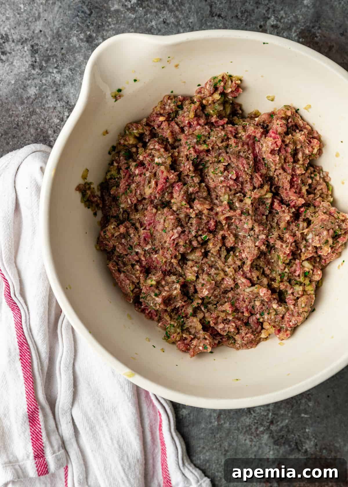 overhead: raw ground meat mixture in white mixing bowl