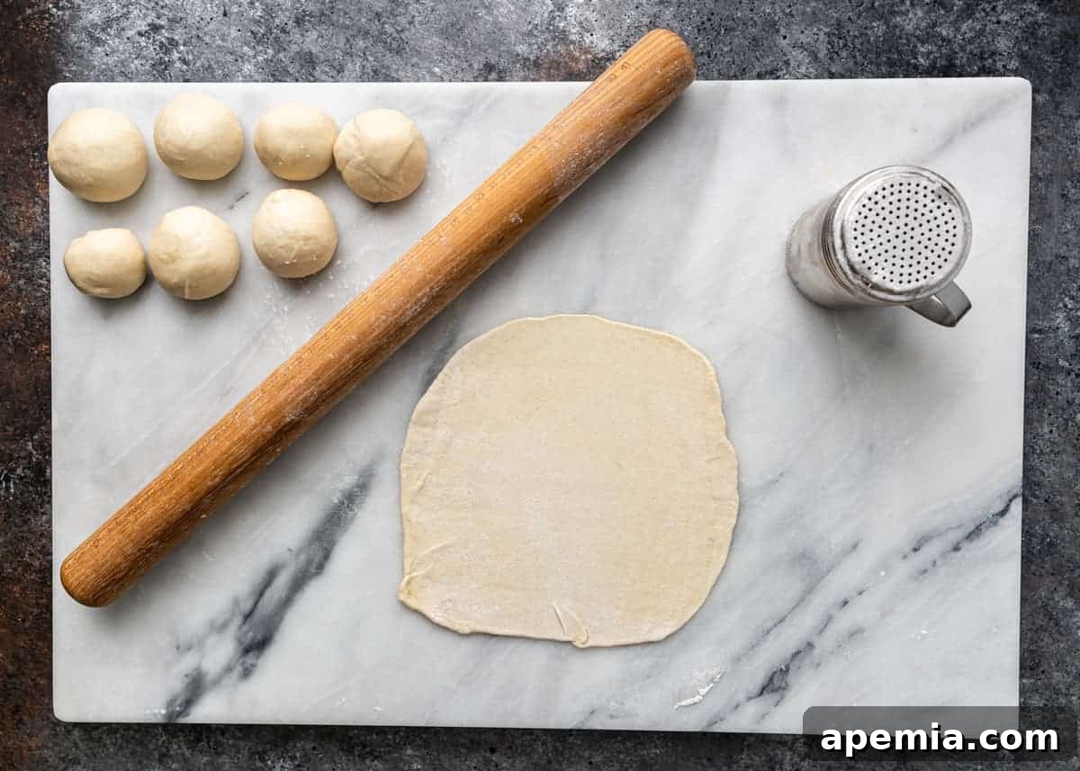 marble pastry slab with wood rolling pin and small balls of chebureki dough