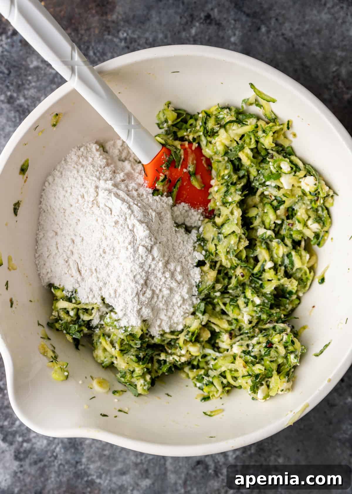 mixing ingredients in bowl to make batter for Greek zucchini fritters