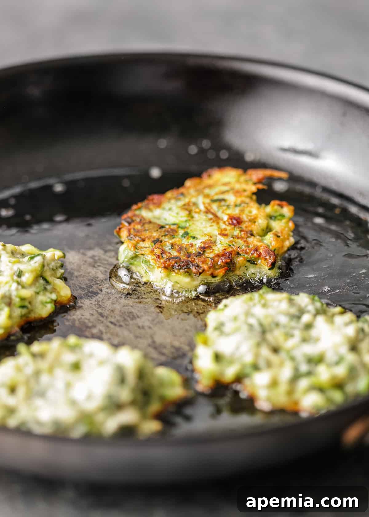 crispy fried squash patties cooking in pan of oil