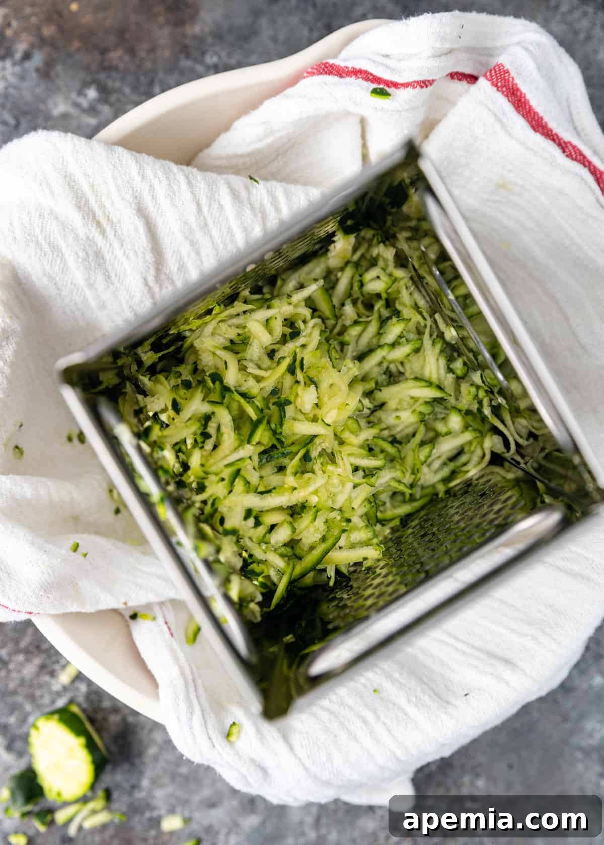 grating zucchini onto white kitchen towel for Greek fritters (Kolokithokeftedes)