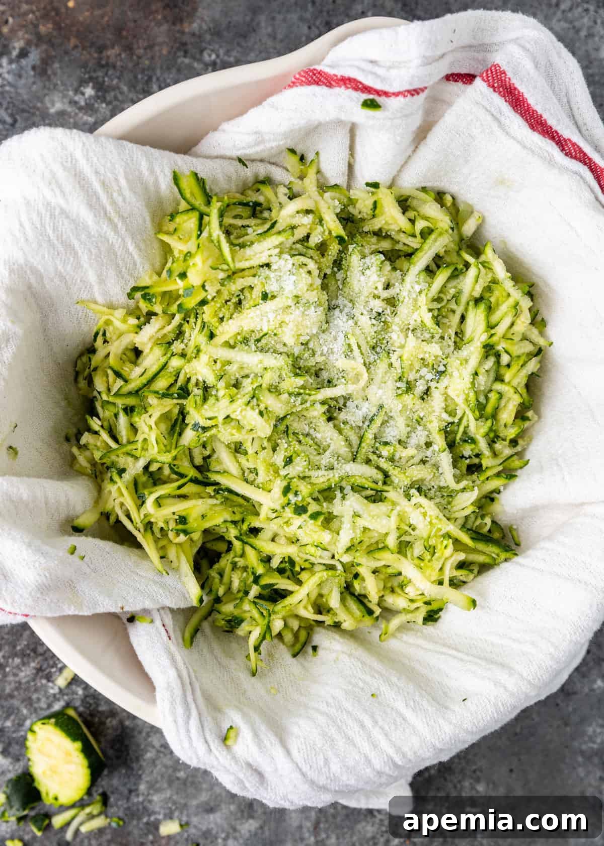 draining water from shredded salted zucchini on white kitchen towel