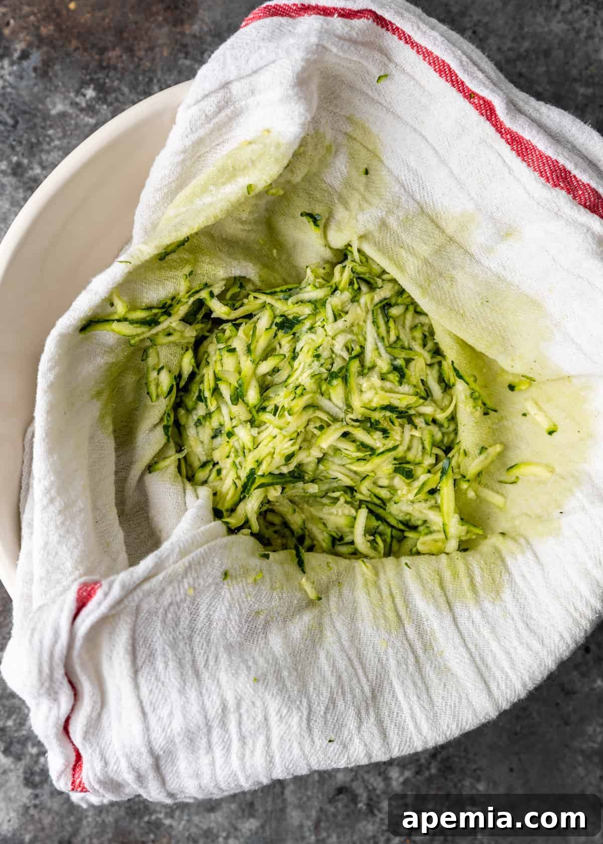 pile of shredded squash on white kitchen towel, squeezed of excess moisture for making Greek fritters