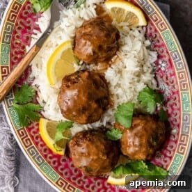 overhead image: plate of Asian lemon cilantro chicken meatballs served over white rice with lemon slices