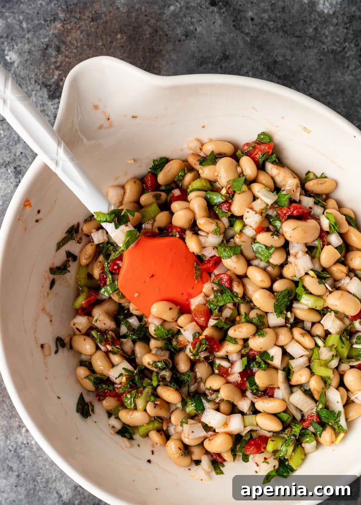 overhead: stirring ingredients together in mixing bowl for gigantes