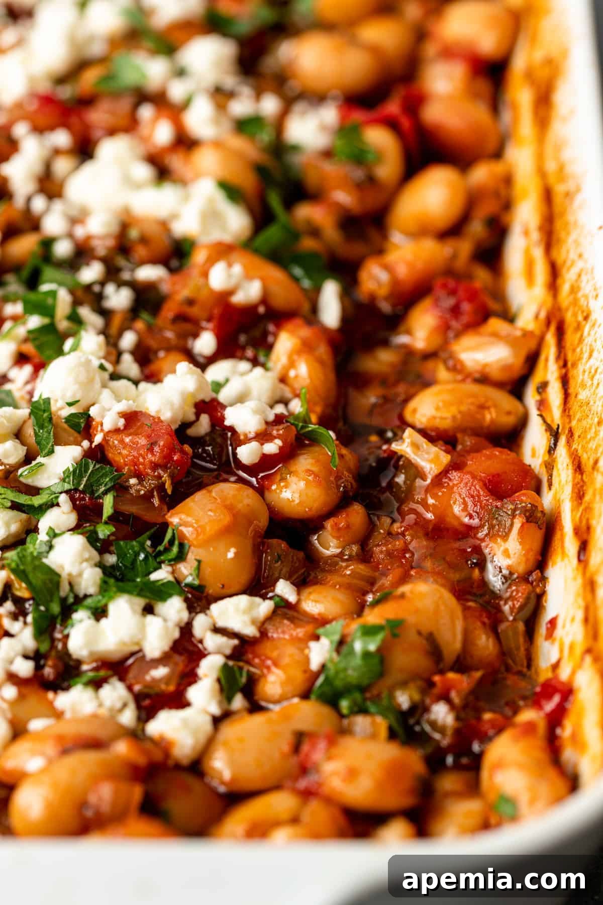 overhead: casserole dish of Greek baked beans in tomato sauce with parsley and feta cheese