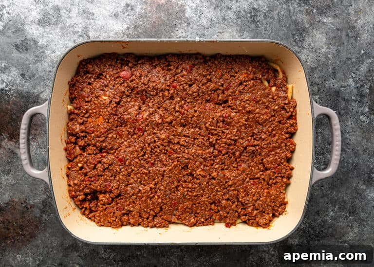overhead process shot: layer of meat sauce in casserole dish for pasticcio
