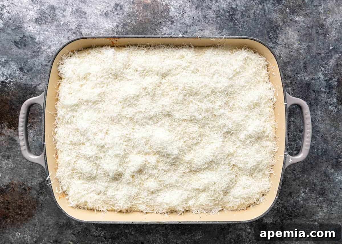overhead: layer of shredded kefalotyri cheese in baking dish for pastitsio recipe