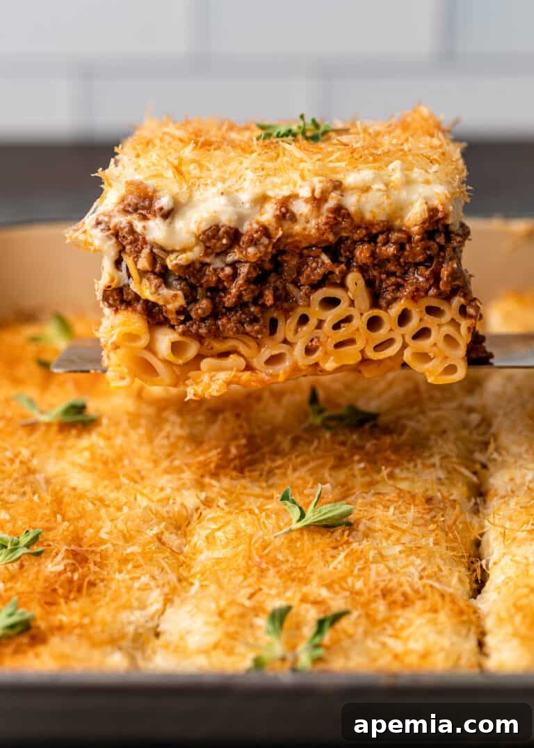 large serving of my pastitsio recipe sits on spatula above the pan
