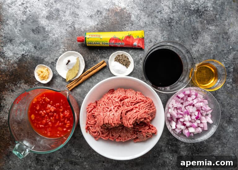 bowl with raw ground meat and smaller bowls of ingredients for pasticcio