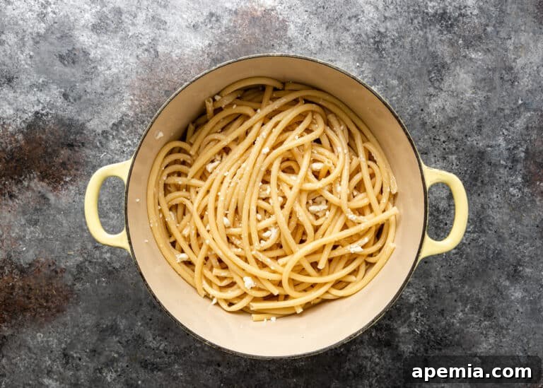 overhead: pot of cooked bucatini pasta sprinkled with feta cheese