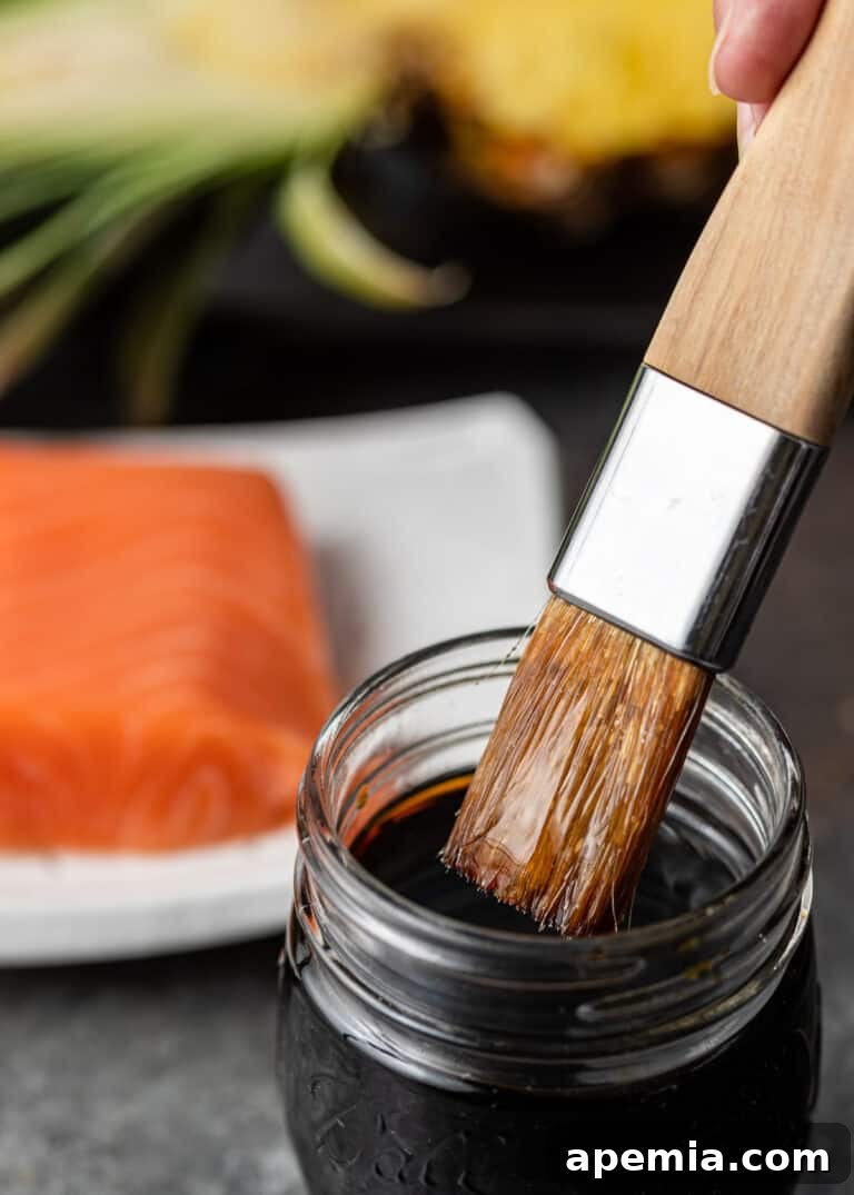 Tropical Pineapple Teriyaki 5 Close-up of a basting brush being dipped into a jar of rich, amber Asian marinade, highlighting its thick texture.