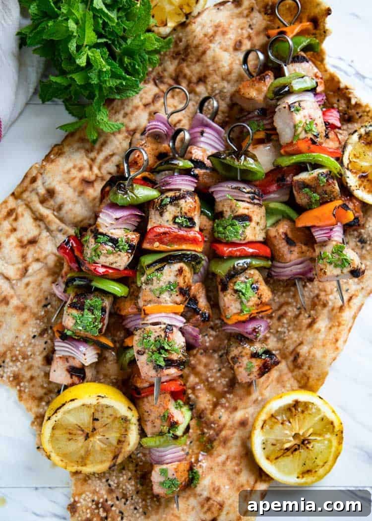 Overhead shot of pork shish kabobs and grilled lemon served on lavash flatbread.