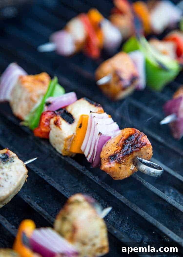 Pork shish kebab skewers with vegetables grilling over open flame.