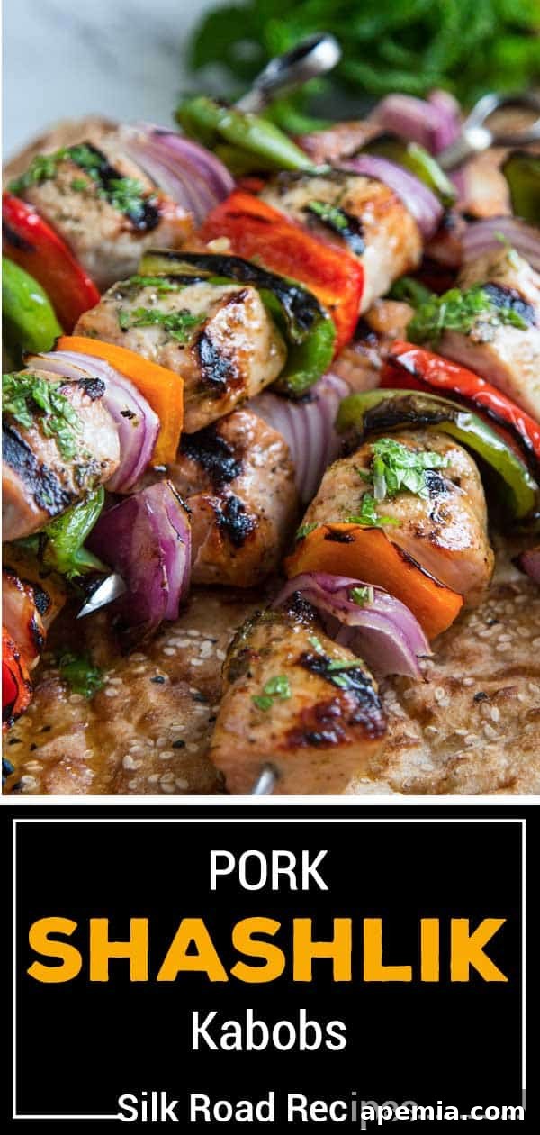 Titled image showing a platter of pork shashlik kabobs with grilled lemons and fresh mint garnish.
