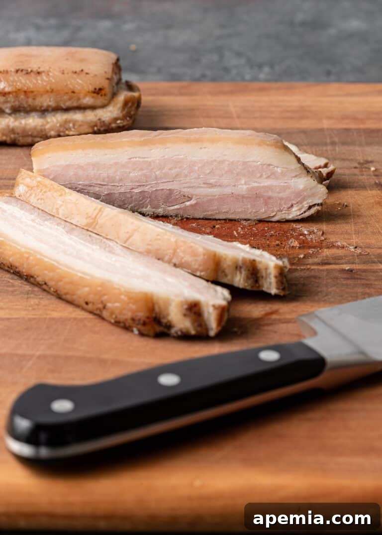 Perfectly roasted and sliced pork belly pieces arranged on a cutting board, ready for searing and assembly.