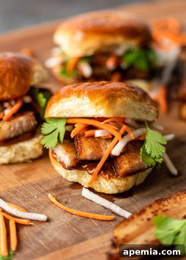 Artistically arranged fried pork belly sliders topped with vibrant pickled vegetables and fresh cilantro on a rustic wood cutting board.