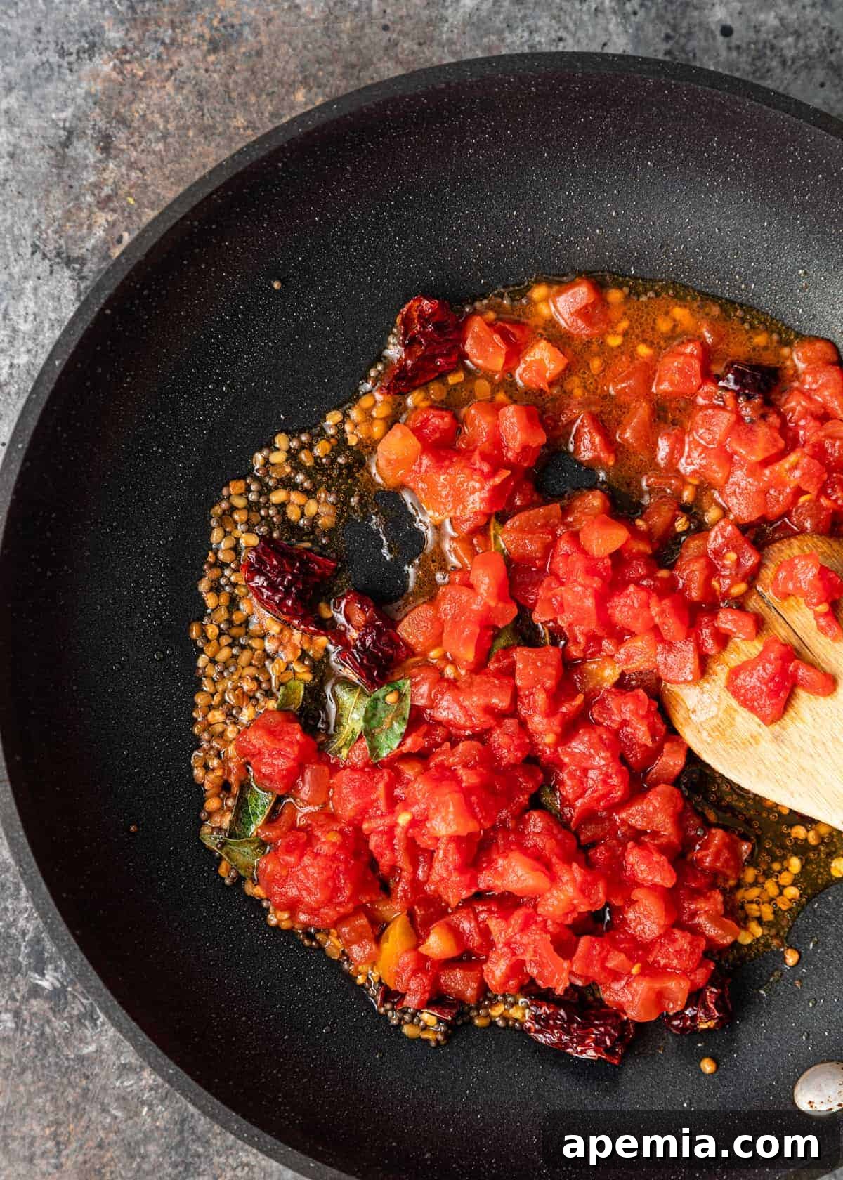 overhead closeup: making tomato pachadi in black skillet