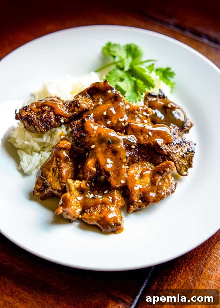 Close-up shot of Chinese Beef Curry on a white plate with rice and fresh herbs, ready to be enjoyed.