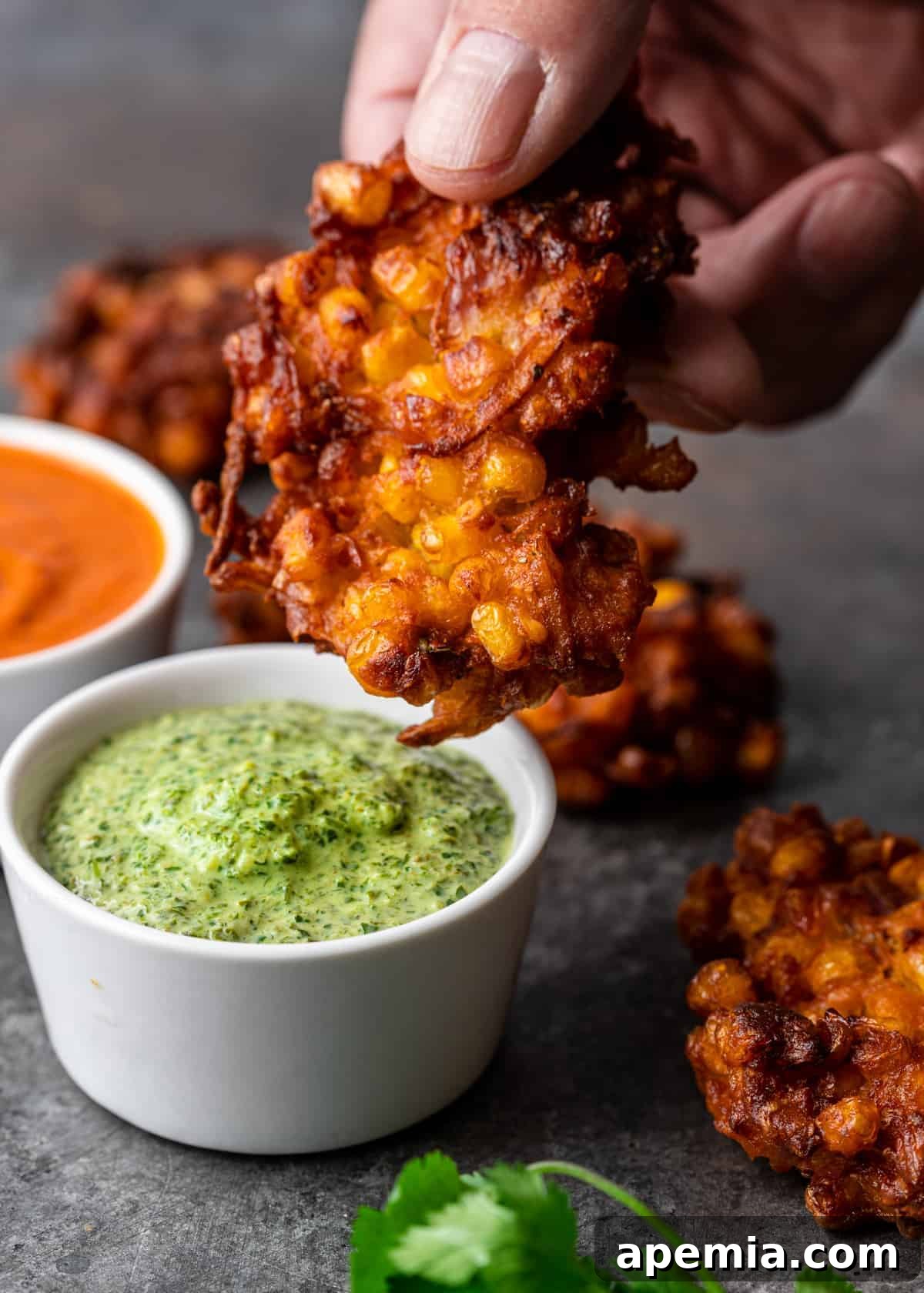 dipping corn fritter into coriander mint chutney