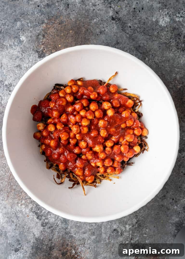 overhead process shot: adding the tomato sauce and chickpeas on top of the onions