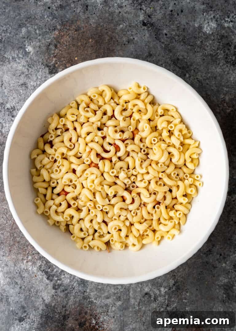 overhead process shot: adding cooked elbow macaroni on top