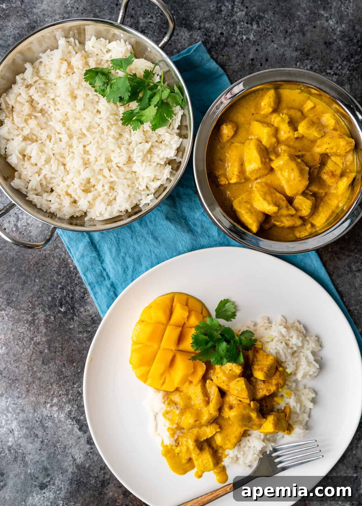 A delectable spread featuring a bowl of white rice and a rich mango curry, with a plated serving below