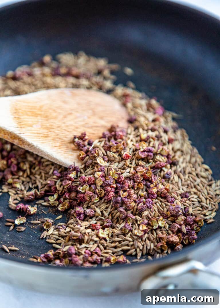Close up image: wooden spoon stirring Xinjiang spice blend in a bowl.