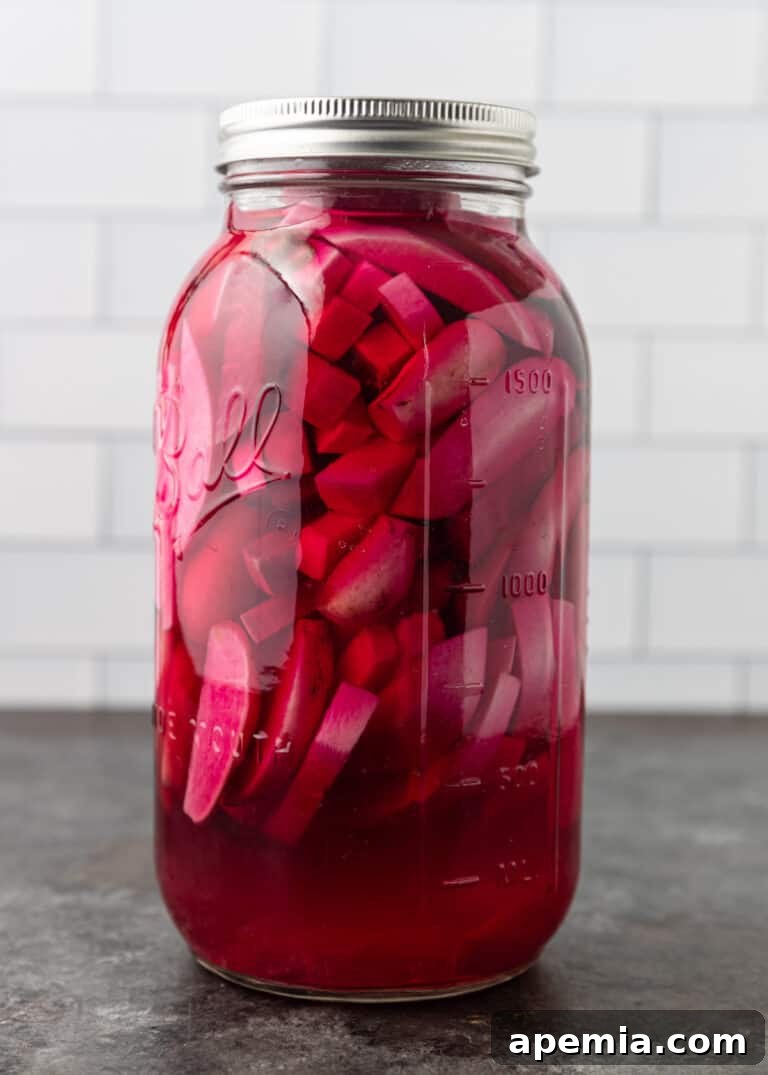 Side view of pickled turnips in a mason jar with a rich pink brine on Day 4.