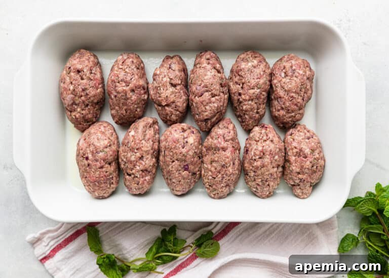 Overhead shot of uncooked Soutzoukakia Smyrneika, perfectly shaped and ready for baking
