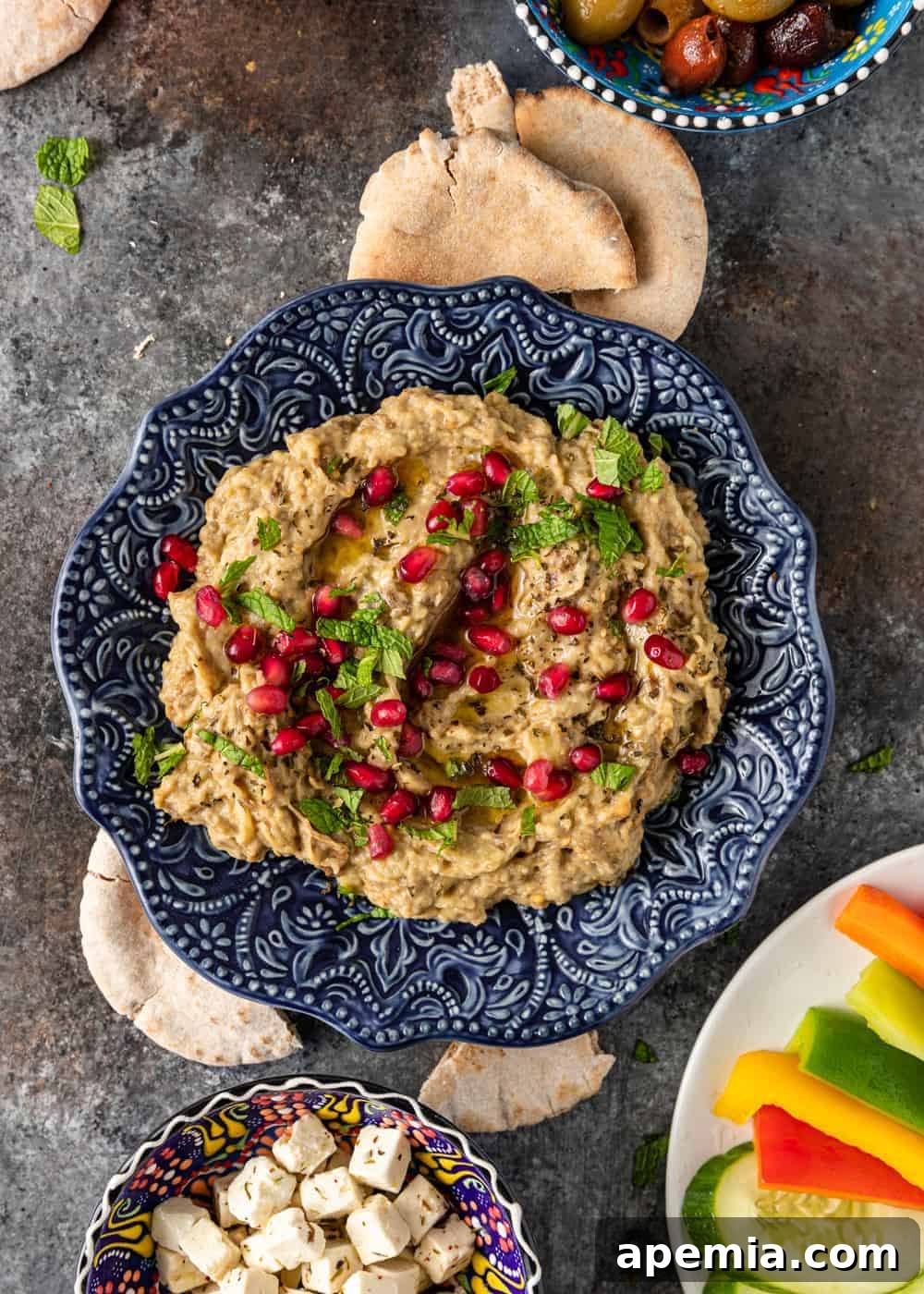 Smoky Mutabal Eggplant Dip 4 An appetizing spread of Mutabal dip surrounded by an assortment of raw vegetables and cheese, perfect for dipping.