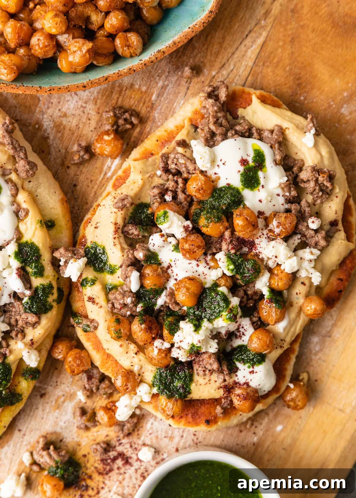 Overhead view of a beautiful mezze platter arranged on a wooden board, featuring freshly made Mediterranean flatbread pizzas alongside a bowl of perfectly spiced chickpeas, ideal for sharing.
