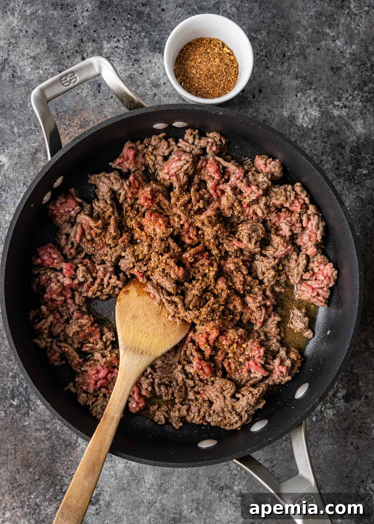 Overhead shot of ground lamb browning in a hot skillet, ready to be seasoned for a Mediterranean flatbread pizza.