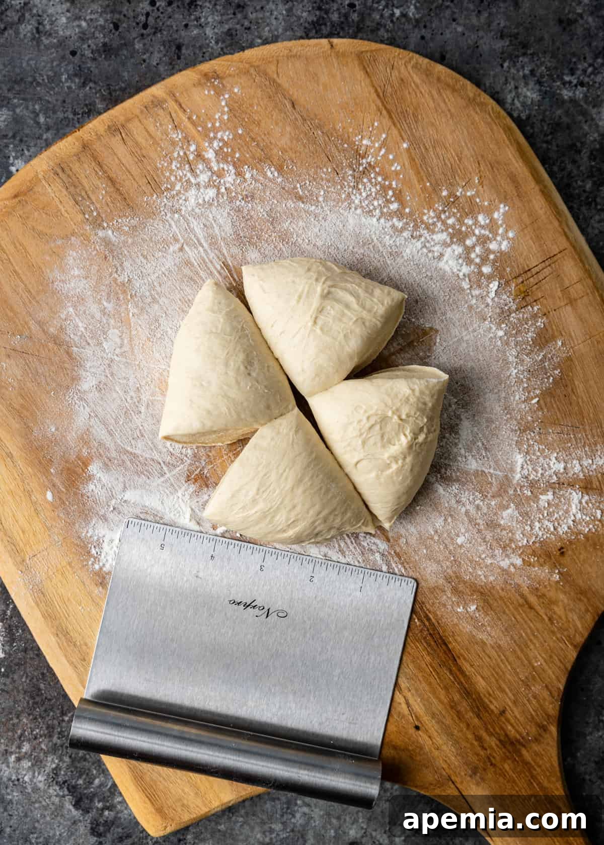 Four equal portions of pizza dough neatly arranged on a floured wooden cutting board, prepped for shaping into flatbreads.