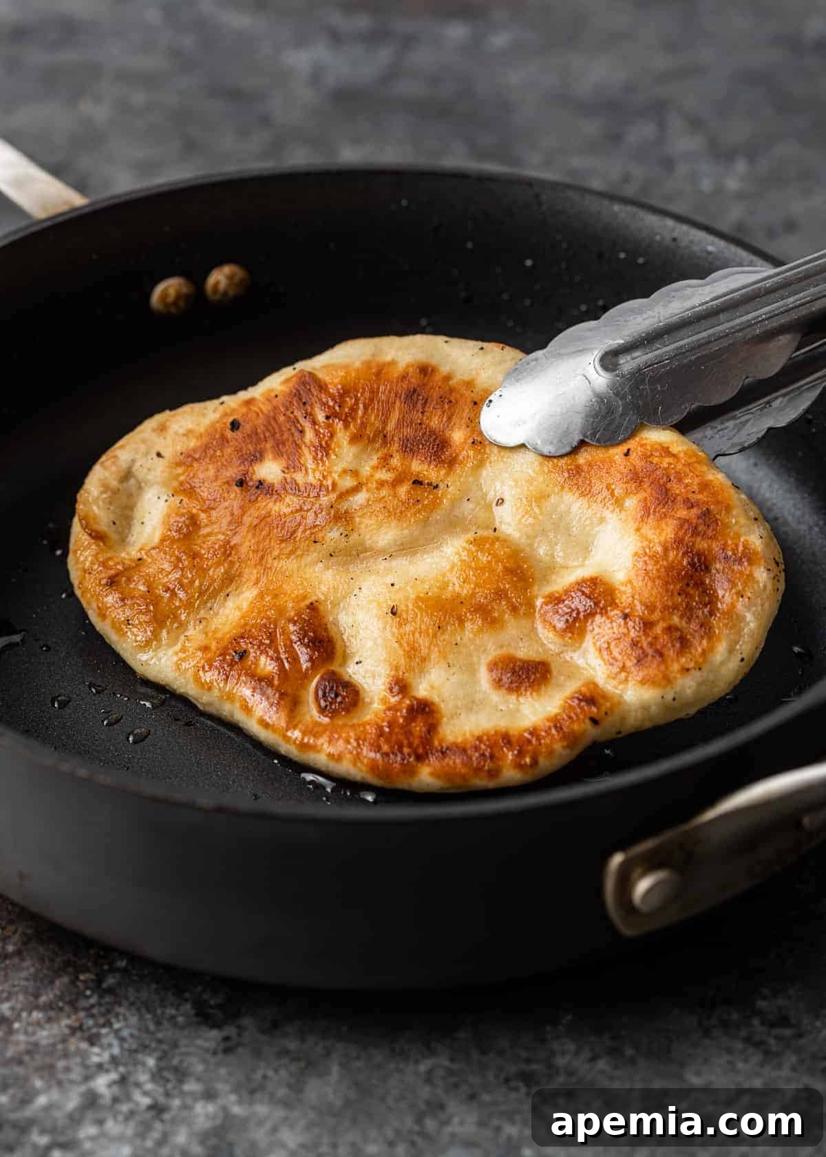 Close-up of dough being expertly pan-fried in olive oil within a skillet, creating a perfectly crispy base for the Mediterranean pizza.