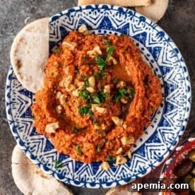 red pepper spread in a blue in white bowl with sliced pita