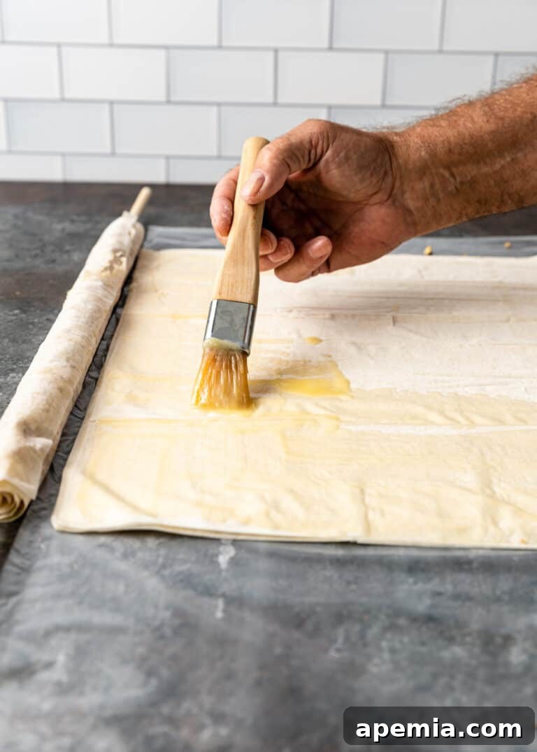 brushing phyllo dough with butter for Greek baklava, adding more richness
