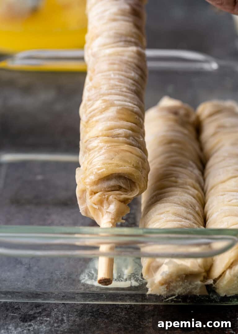 phyllo dough wrapped around wooden dowel for saragli, showcasing the rolling technique