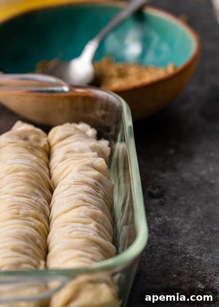 close up of greek baklava rolls in glass baking pan, ready for the oven