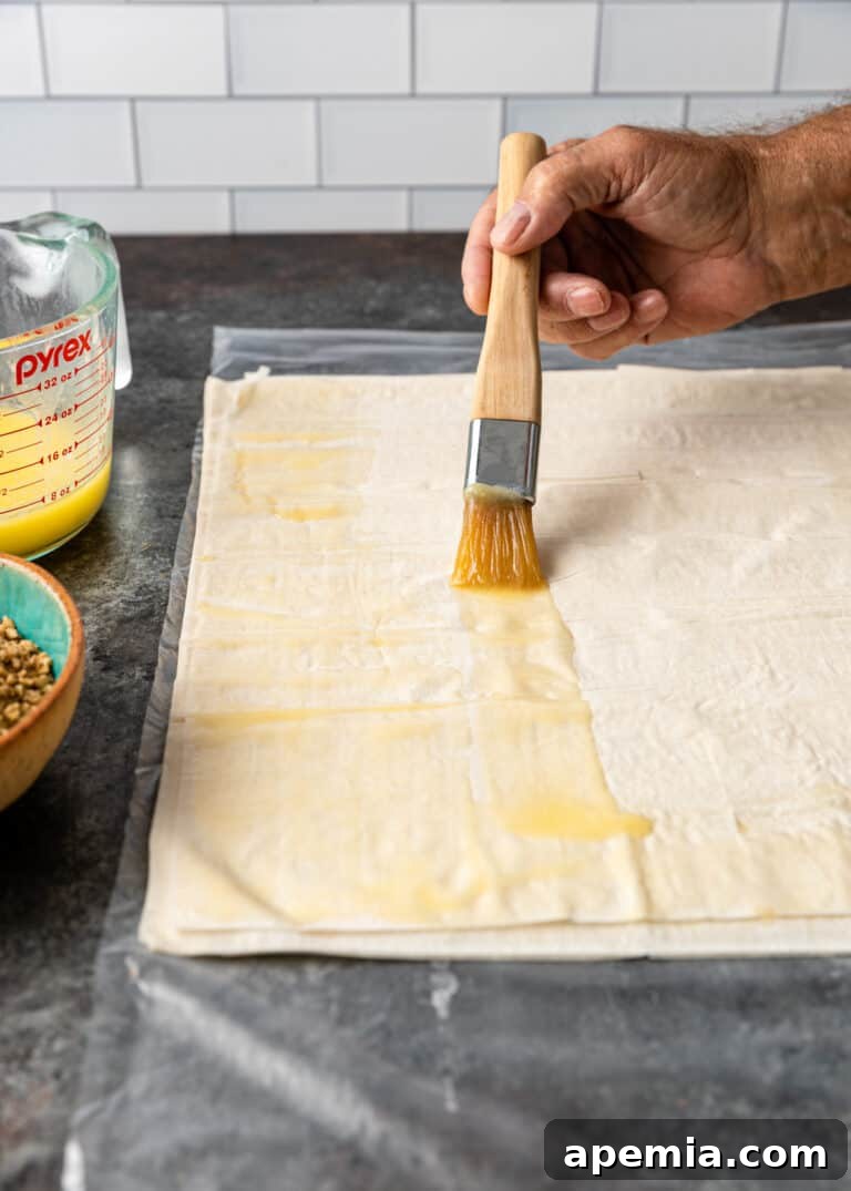 brushing melted butter on sheet of phyllo for baklava recipe, a crucial step for crispiness