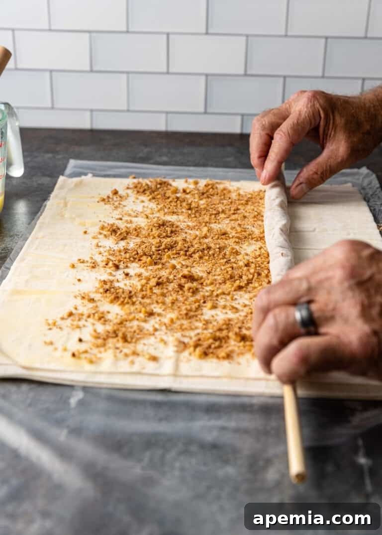 rolling phyllo pastry with baklava filling around a dowel