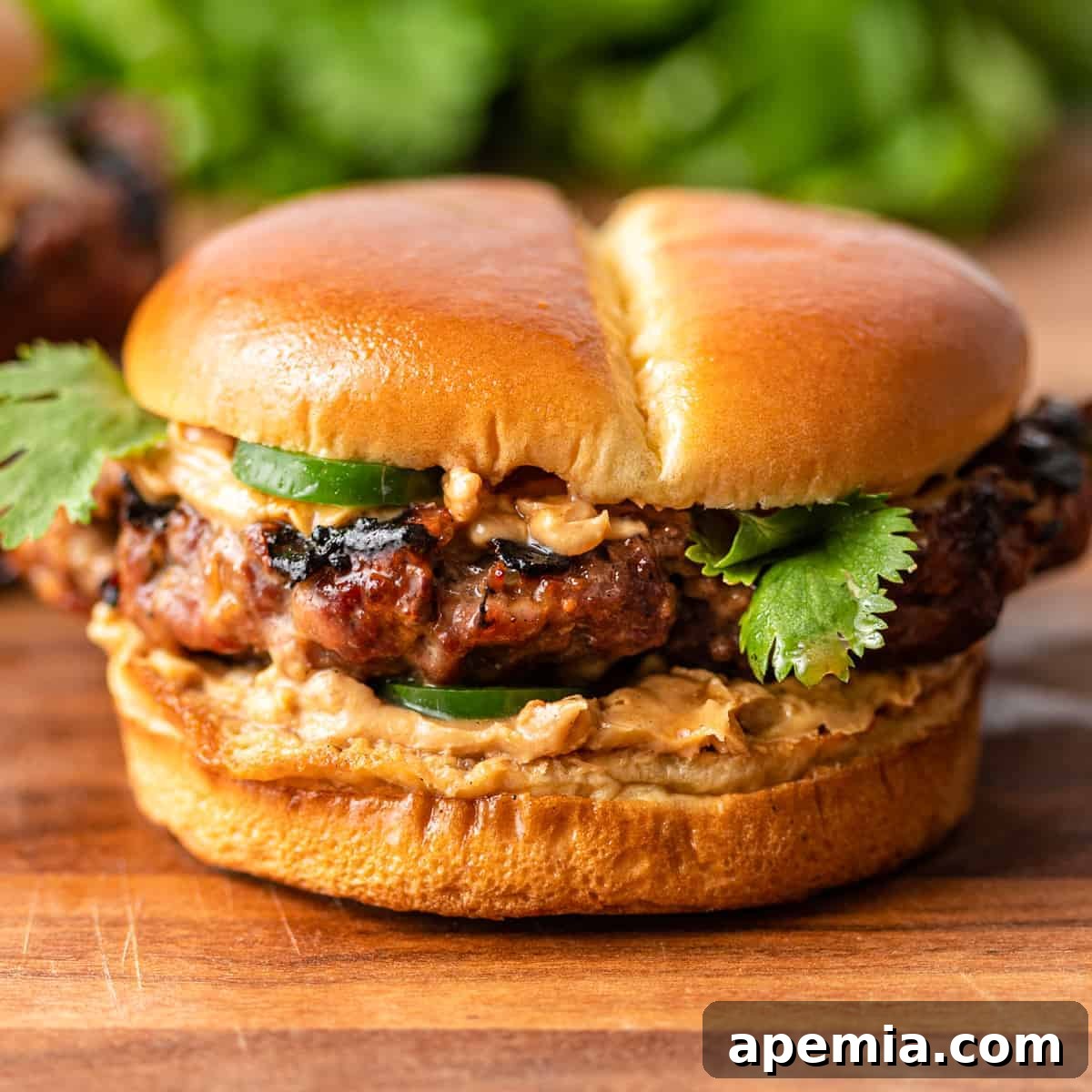 ground pork burger with jalapenos and spicy peanut sauce on soft bun