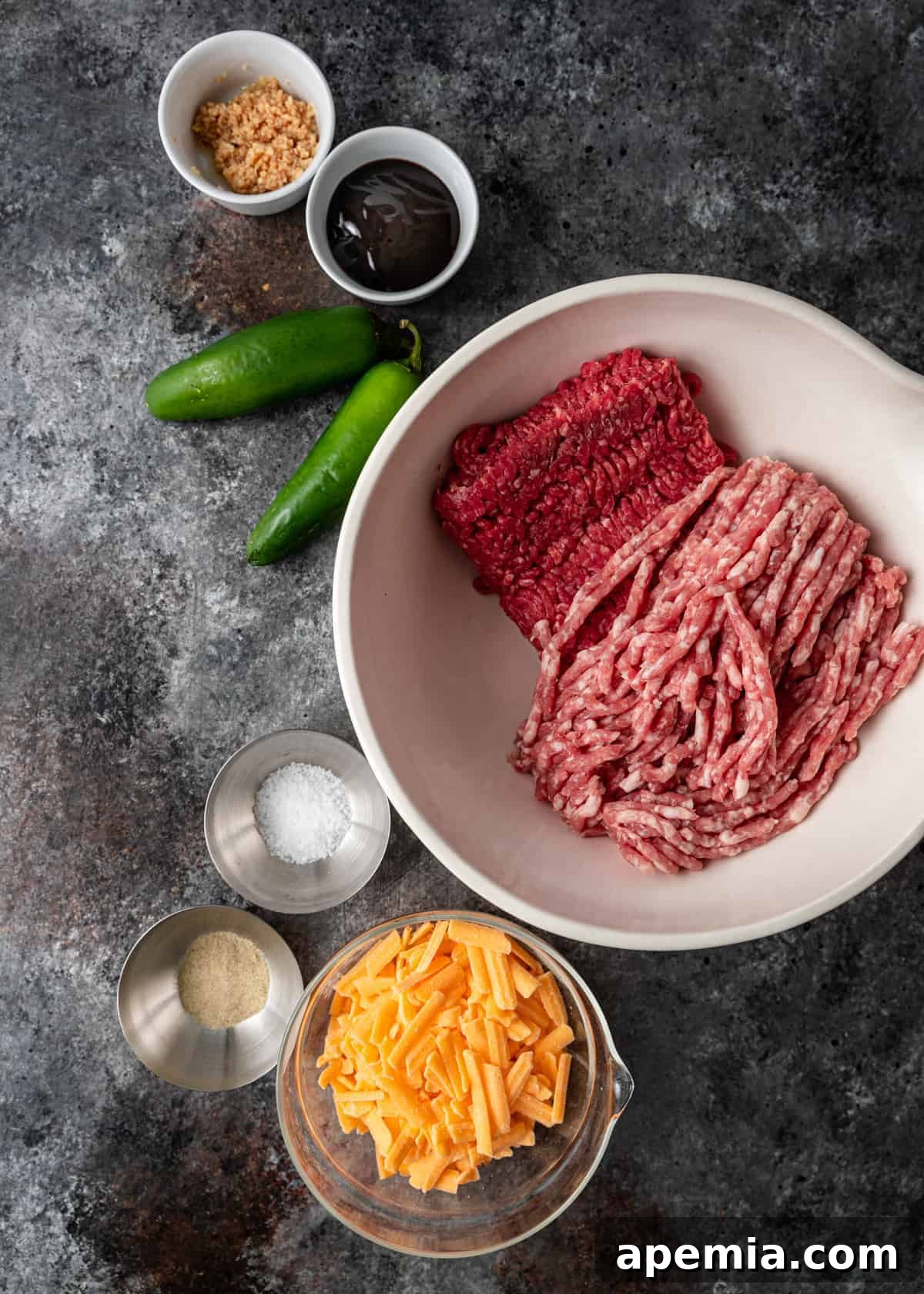 overhead: fresh ground pork and ground beef in mixing bowl next to smaller bowls of ingredients to make Thai burger recipe