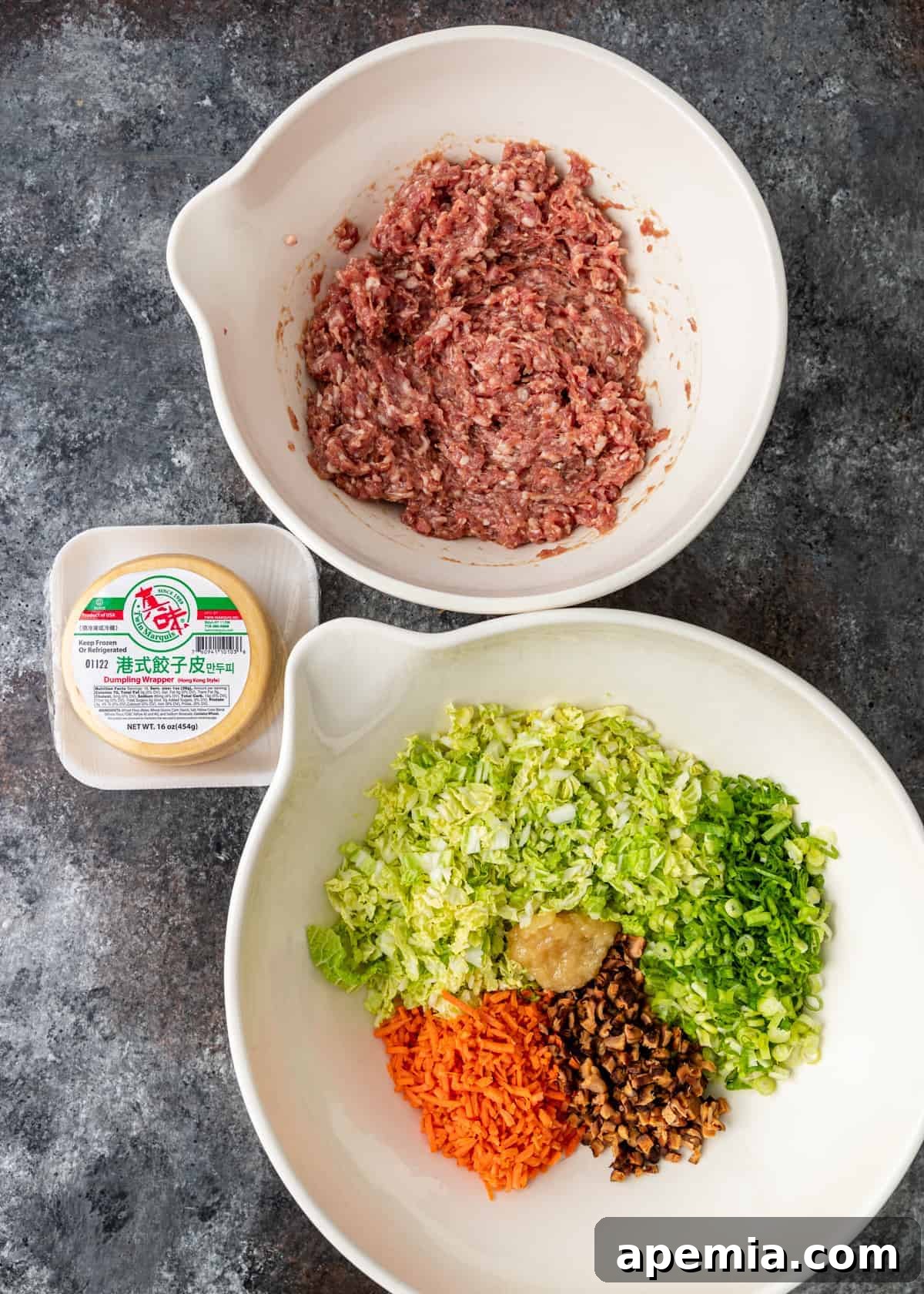 overhead: ground pork and various fresh vegetables in separate bowls, ready for making pork potstickers