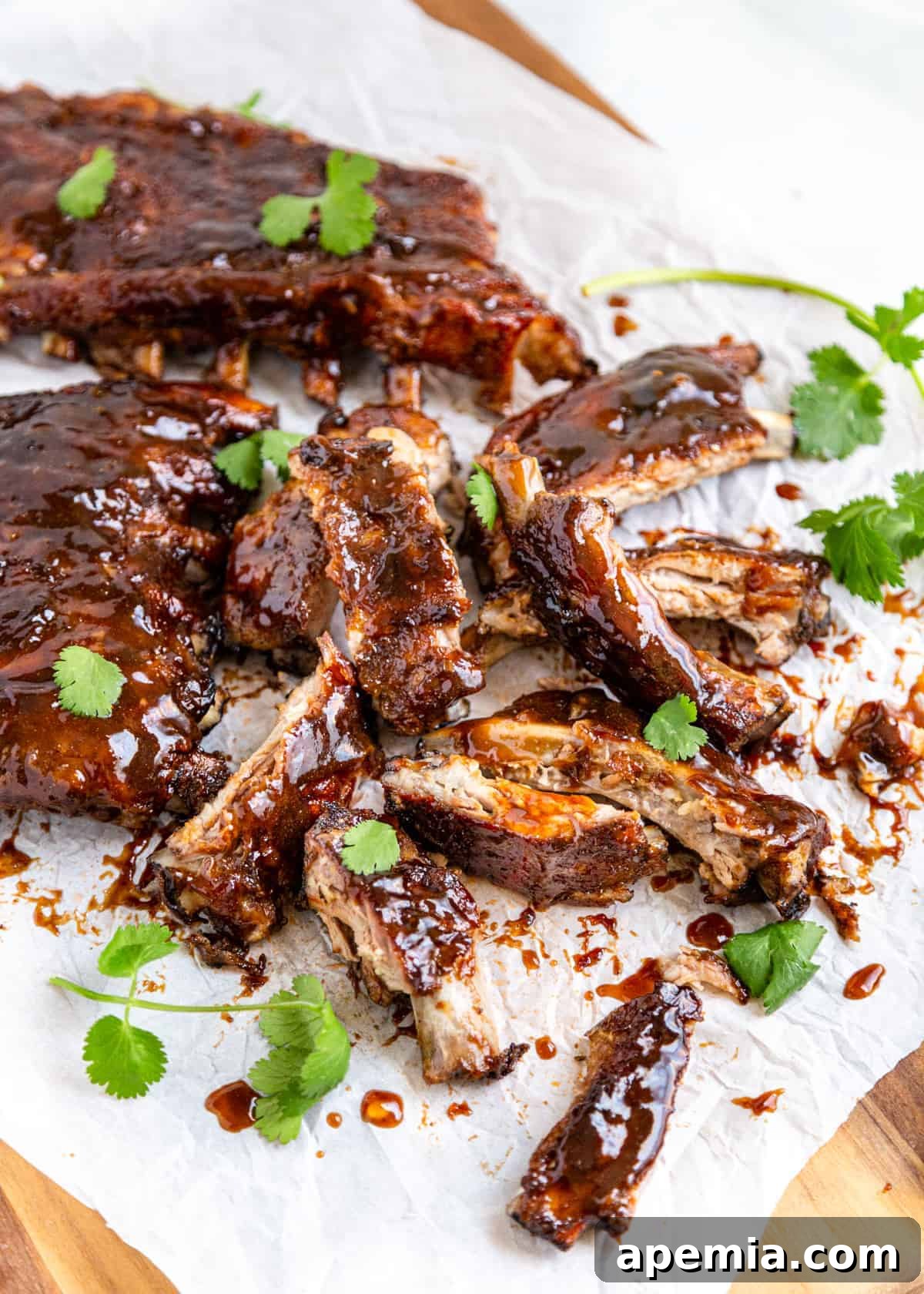 Sweet and sour pork ribs arranged on a piece of parchment paper, garnished with fresh parsley.