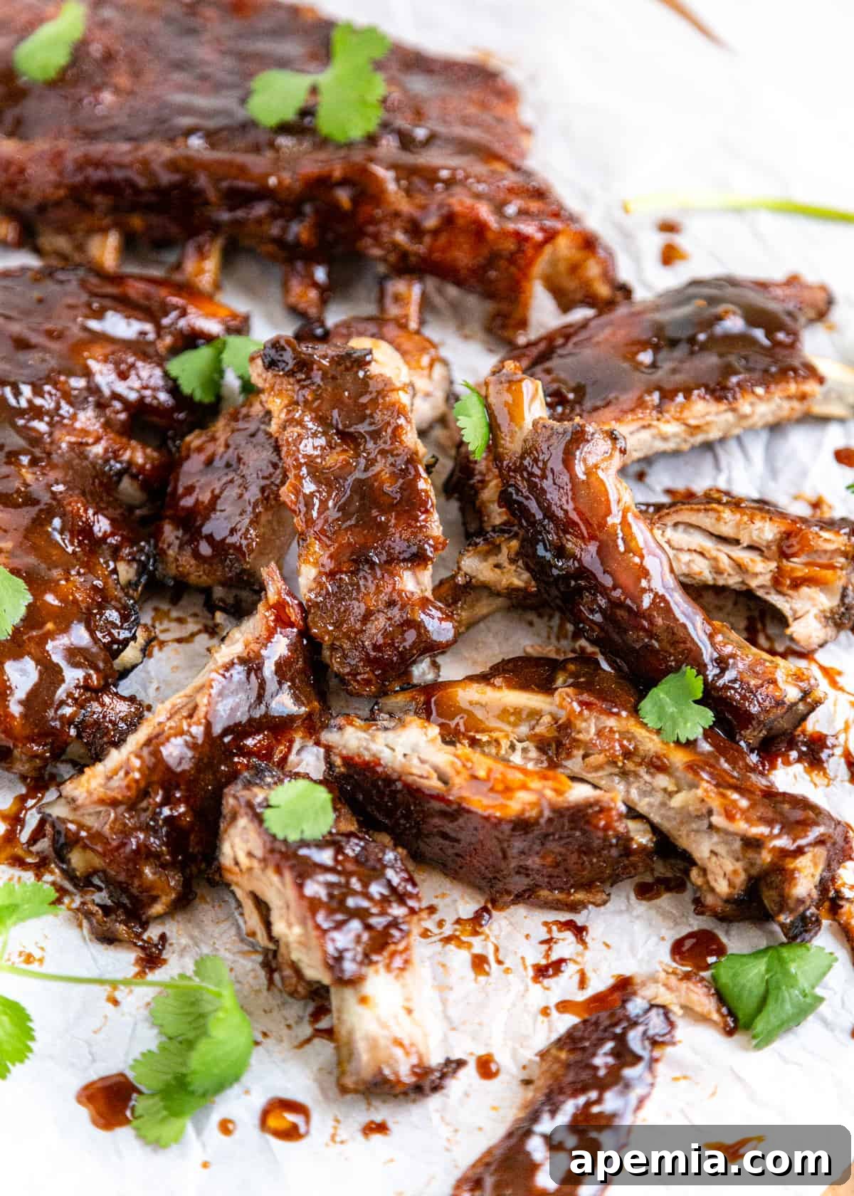 Piles of saucy sweet and sour ribs on parchment paper, ready to be served.