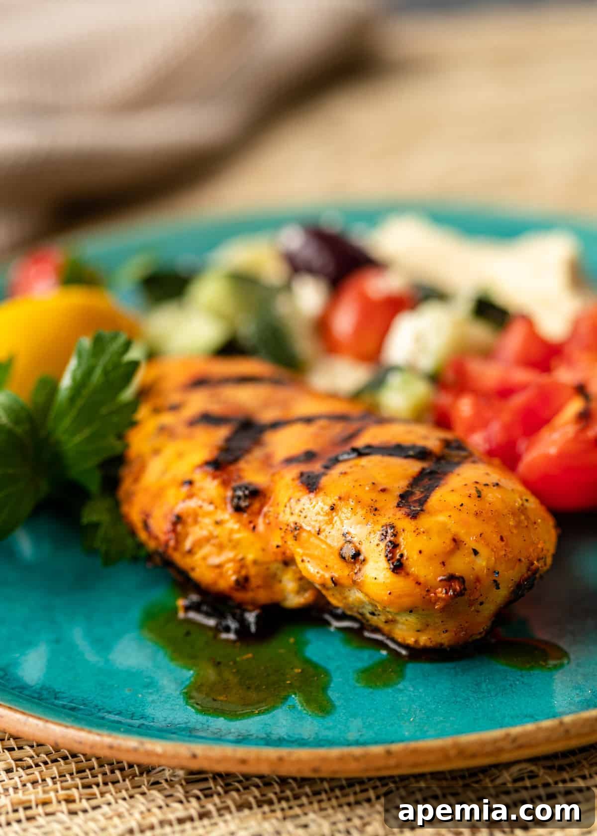 Close-up side view of grilled saffron chicken pieces presented on a blue plate, highlighting its appetizing char marks and golden glaze.