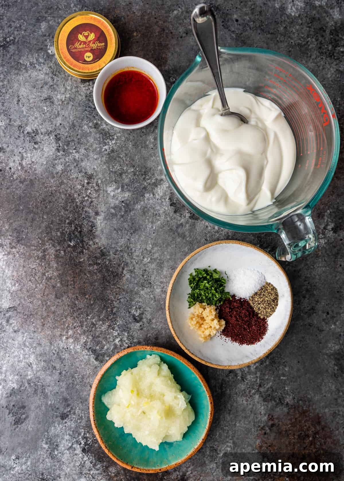 Overhead view of all fresh ingredients needed for preparing the saffron chicken marinade, neatly arranged on a counter.
